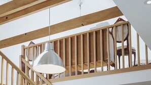 A wooden staircase with a pendant light, a dining area with a table and chairs, and a child's toy house. - Apartments Mozinetova hisa (Dobrova-Polhov Gradec)