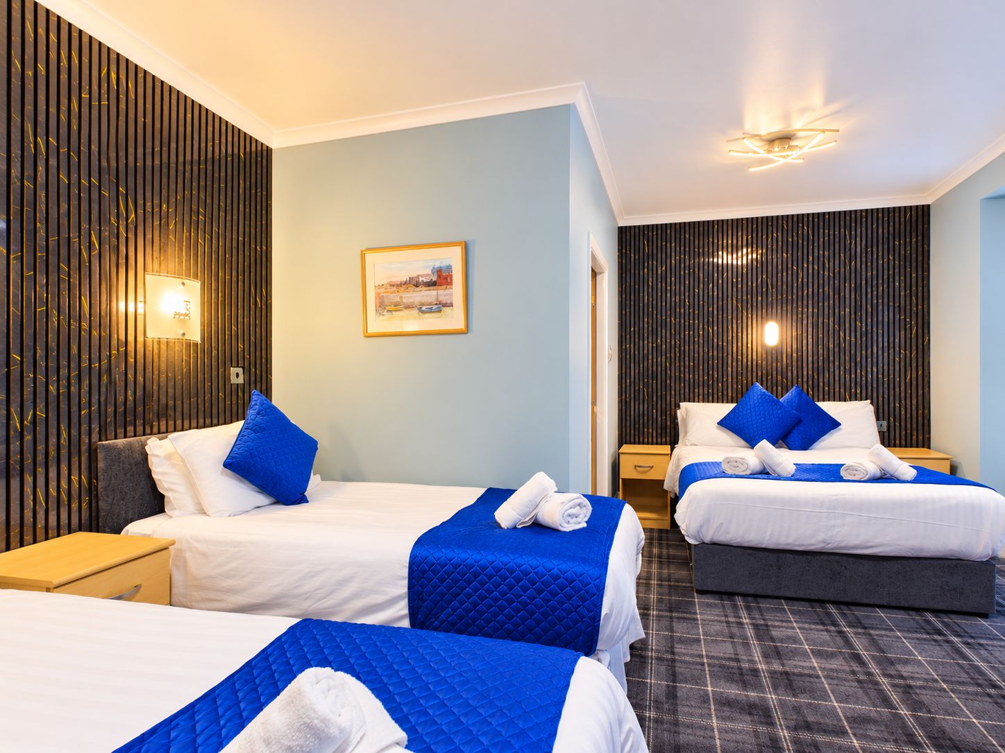 Ein Hotelzimmer mit zwei Betten, einem Bild an der Wand und einer Rezeption.