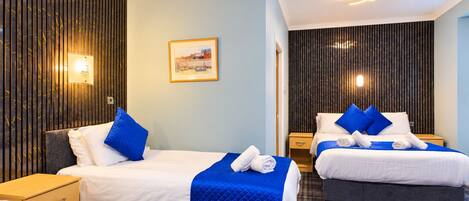 Ein Hotelzimmer mit zwei Betten, einem Bild an der Wand und einer Rezeption.