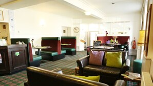 A hotel lobby with green and black leather seating, a reception desk, and a fire extinguisher. - Homesly The Station Hotel (Banff)