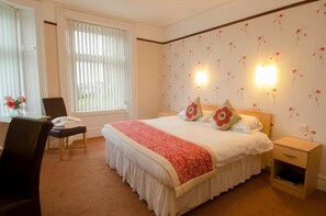 A neatly arranged bedroom with a large bed, two bedside tables, a chair, and a desk. - Homesly The Station Hotel (Banff)