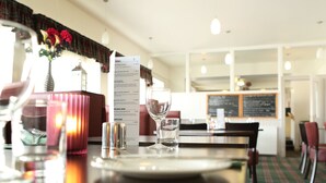 A restaurant setting with a menu, a glass of water, and a candle on the table. - Homesly The Station Hotel (Banff)
