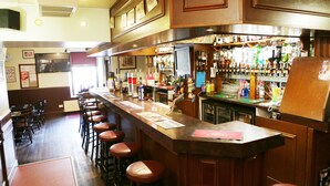 A bar area with stools, a counter, and a variety of bottles. - Homesly The Station Hotel (Banff)