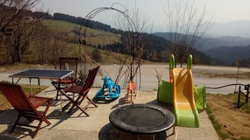 Relax and play in our outdoor recreational area, featuring a ping pong table, play structure, slide, and trampoline.
