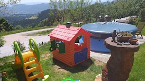 Zona de juegos infantiles con un tobogán, una casita y una piscina.