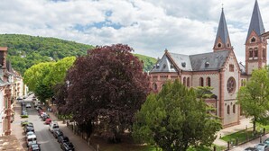 A church with a prominent steeple, surrounded by a street lined with parked cars and trees. - Hotel Krokodil (Heidelberg)