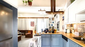 A modern kitchen with blue cabinets, a stainless steel refrigerator, and a dining area with a table and chairs. - Casa Ithomi, 3 Bedroom Maisonnet, Old Harbor Chania (Χανιά)