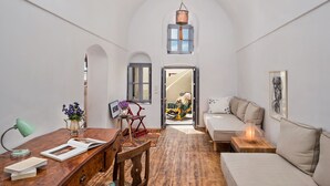 Una habitación con un escritorio de madera, un sofá y vistas a través de una puerta abierta.