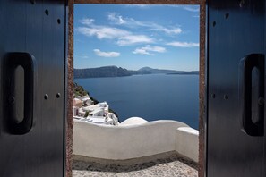 A view through a metal door with a white building and a body of water in the background.
