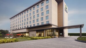 A modern hotel with a flat facade, large windows, and a covered entrance area. - Holiday Inn Express Kolkata Airport by IHG (Barakpur)