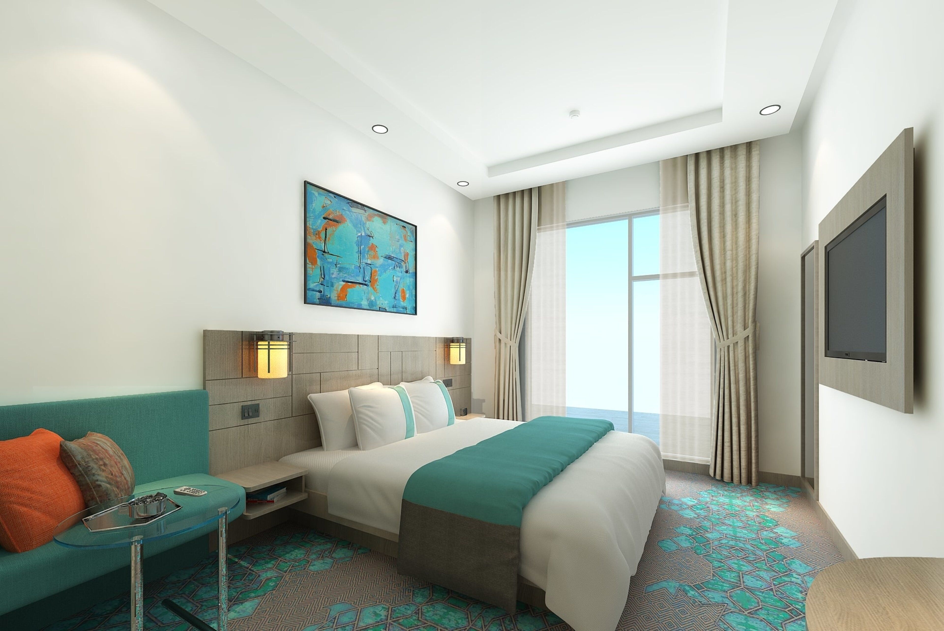 Habitación de hotel con cama, sofá, una mesita, un cuadro en la pared y un ventanal con cortinas.