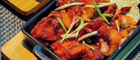 A dish of chicken with vegetables in a cast iron skillet.