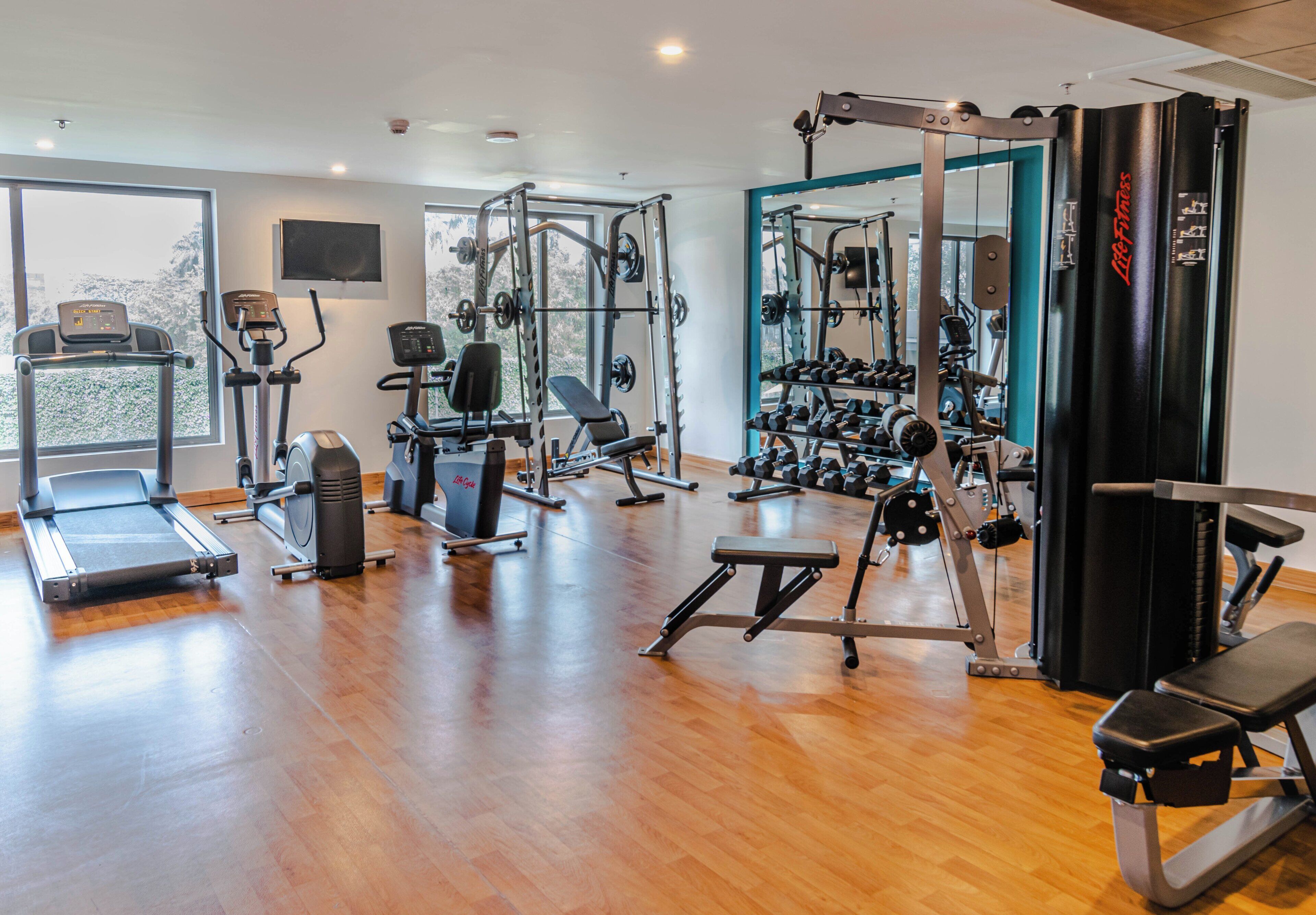 A gym with various exercise equipment, including treadmills, weight machines, and free weights.