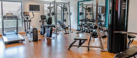 Un gimnasio con equipo de ejercicio variado, incluyendo cintas de correr, máquinas de pesas y pesas libres.