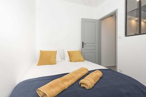 Une chambre à coucher avec un lit, deux oreillers, une porte et un luminaire fixé au mur.