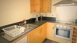 A kitchen with wooden cabinets, a stainless steel oven, and a black countertop. - Harley Serviced Apartments - West Point (Sheffield)