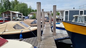 A marina with several boats docked, a wooden walkway, and a small building in the background. - Houseboat Havana (Amsterdam)