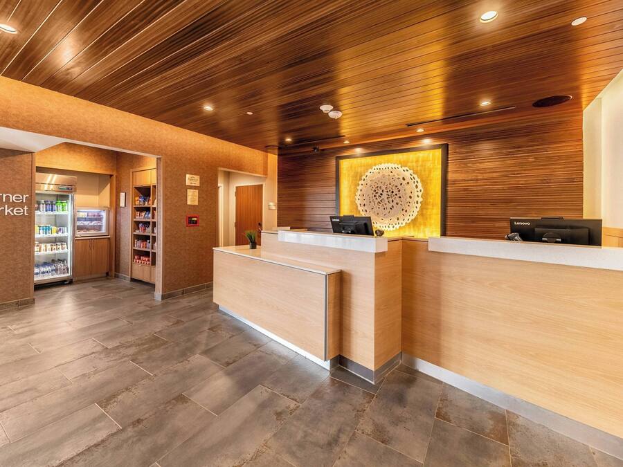 A reception area with a wooden reception desk, a refrigerator stocked with beverages, and a sign for the Corner Market.