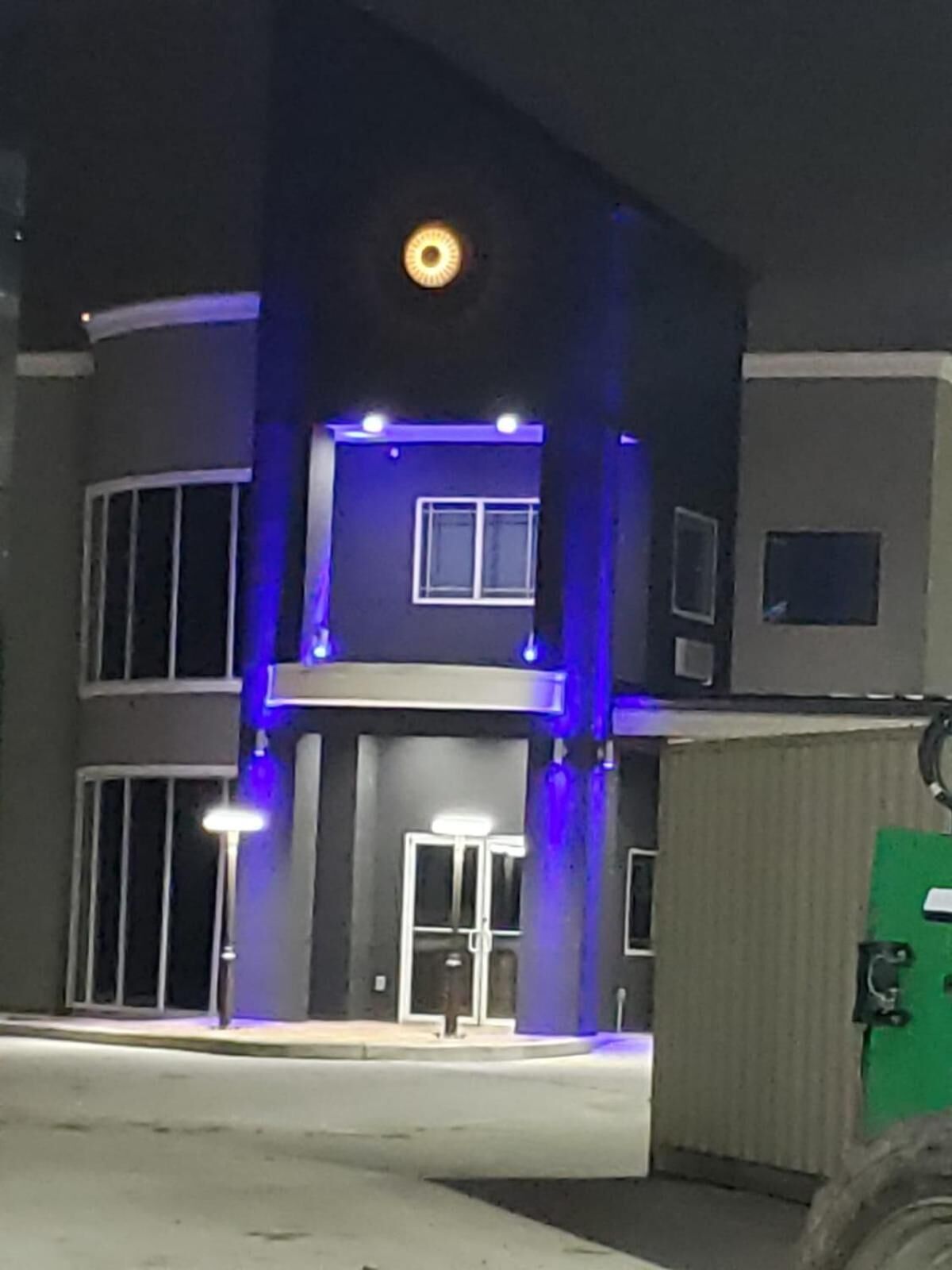 A multi-story building with a central entrance, illuminated by blue lights.