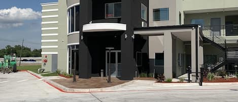 A modern building with a curved facade, a prominent entrance, and a covered area with a staircase.
