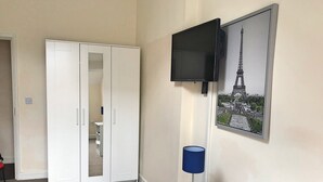 A room with a white wardrobe, a television mounted on the wall, a blue lamp on a small table, and a framed picture of the Eiffel Tower. - Fitzwilliam Street Rooms (Sheffield)