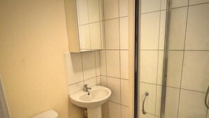 A small bathroom with a sink, toilet, and shower. - Fitzwilliam Street Rooms (Sheffield)