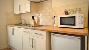 A kitchen with white cabinets, a microwave, and a dishwasher. - Fitzwilliam Street Rooms (Sheffield)