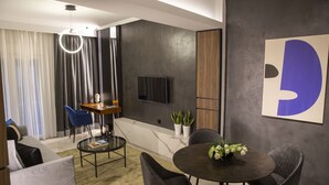 Una sala de estar moderna con un televisor de pantalla plana montado en la pared, una mesa de centro redonda de vidrio y una mesa de comedor con sillas.