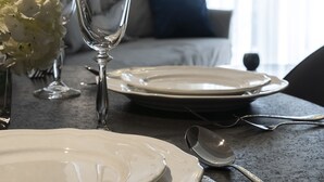Una mesa de comedor con platos blancos, una copa de vino y cubiertos.