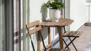 Un conjunto de mesa y banco de madera en un balcón con una planta en maceta.