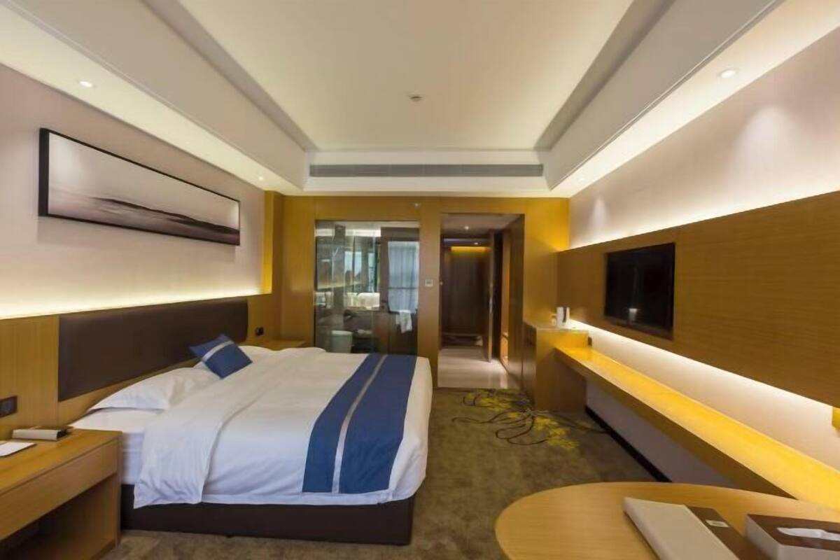 Une chambre d’hôtel comprenant un lit, une table de chevet, une télévision et un bureau avec une chaise.