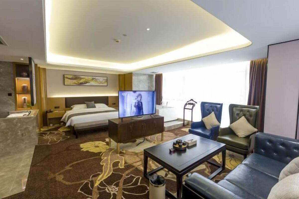 Une chambre d’hôtel comprenant un lit, une télévision, un canapé, une table basse et un bureau.