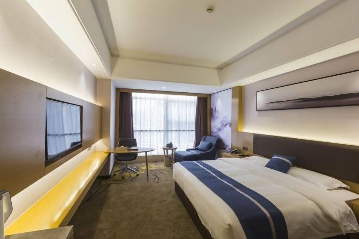 Une chambre d’hôtel moderne, dotée d’un grand lit, d’un bureau, d’une chaise et d’un téléviseur.