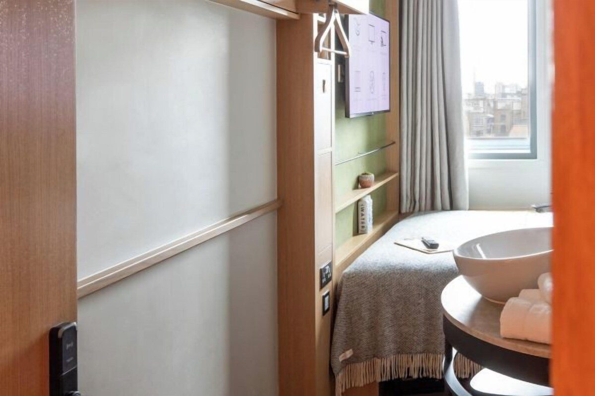A compact bathroom with a sink, towel rack, and a window with curtains.