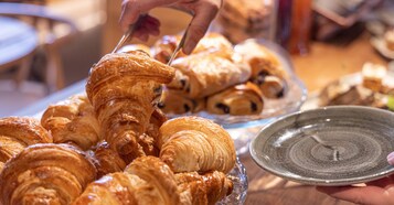 Una selezione di pasticcini, tra cui croissant, su un piatto di vetro.