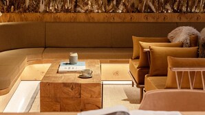 A cozy, modern living room with a curved sofa, a wooden coffee table, and a magazine on a side table. - Wren Urban Nest (Dublin)