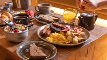 A breakfast setting with various dishes including toast, scrambled eggs, sausages, and a croissant.