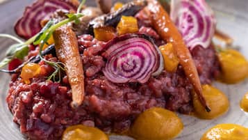 A close-up of a dish with red meat, beets, and yellow vegetables on a plate.