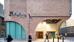 A building with a prominent 'WREN' sign, large arched windows, and a modern interior design. - Wren Urban Nest (Dublin)