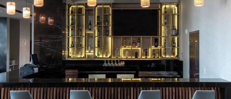 A modern bar area with a black countertop, wooden slatted backrest, and four bar stools.