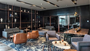 Un interior moderno con un sofá, sillones, una mesa de centro y una mesa de comedor.