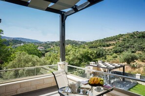 A balcony with a clear view of a hilly landscape, a table with a fruit bowl, and a chair. - Villa 200m to Beach & Amenities w/Pool, Sauna, BBQ (Αλμυρίδα)