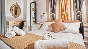 Une chambre d’hôtel avec un grand lit, deux tables de chevet, un miroir et une commode.