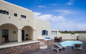 Una villa moderna con piscina, muros de piedra y vistas al paisaje.