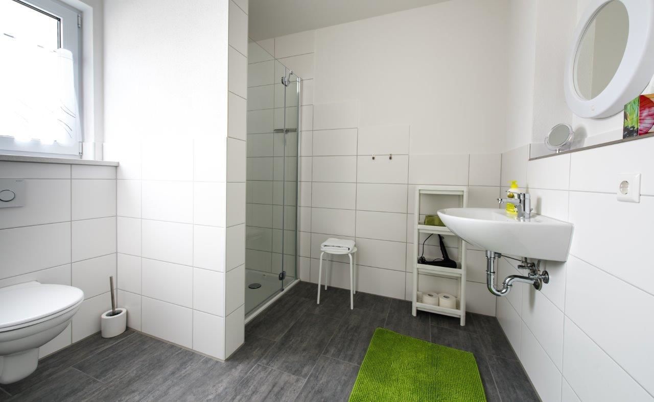 Une salle de bain moderne équipée de toilettes, d’une douche, d’un lavabo et d’un petit tabouret.