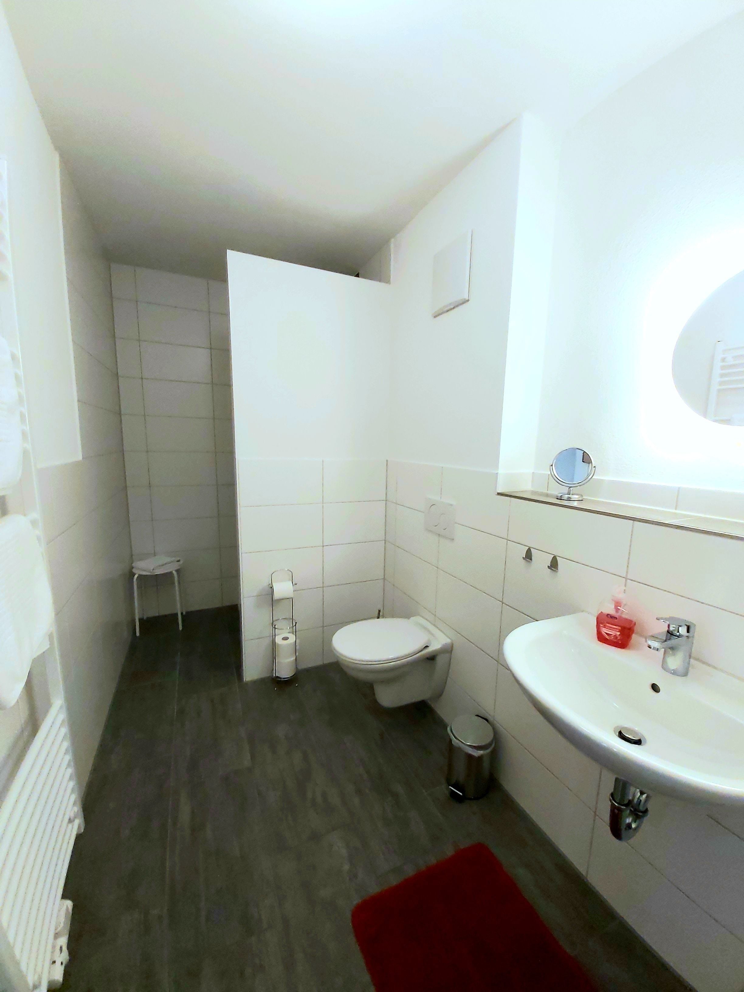 A small, compact bathroom with a toilet, sink, and mirror.