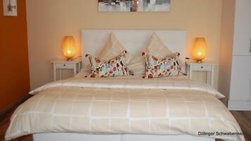 A neatly made bed with a checkered bedspread, two decorative pillows, and two bedside lamps.