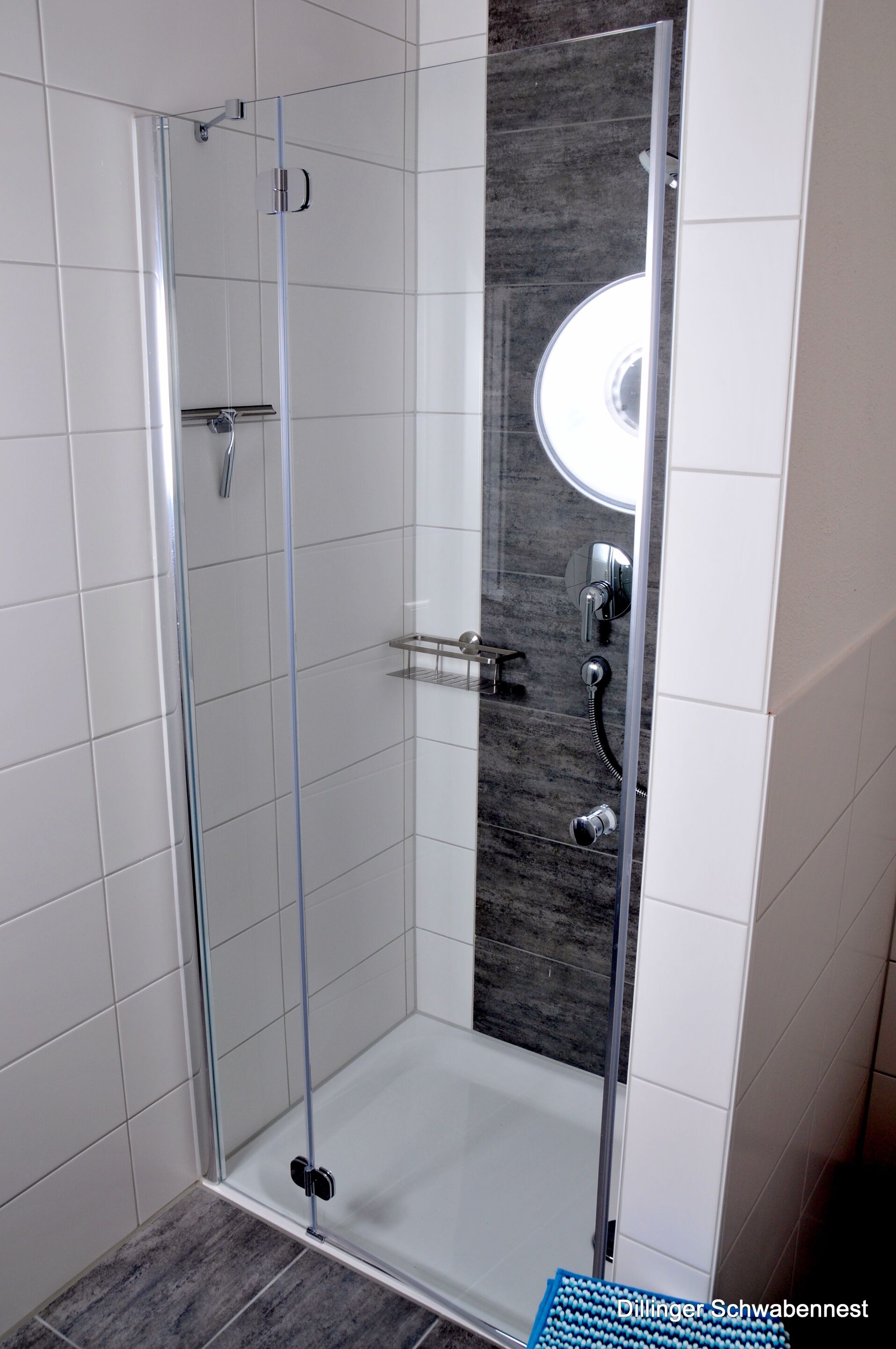 Un box de ducha con paredes de vidrio, un salpicadero de mármol y un lavabo blanco.