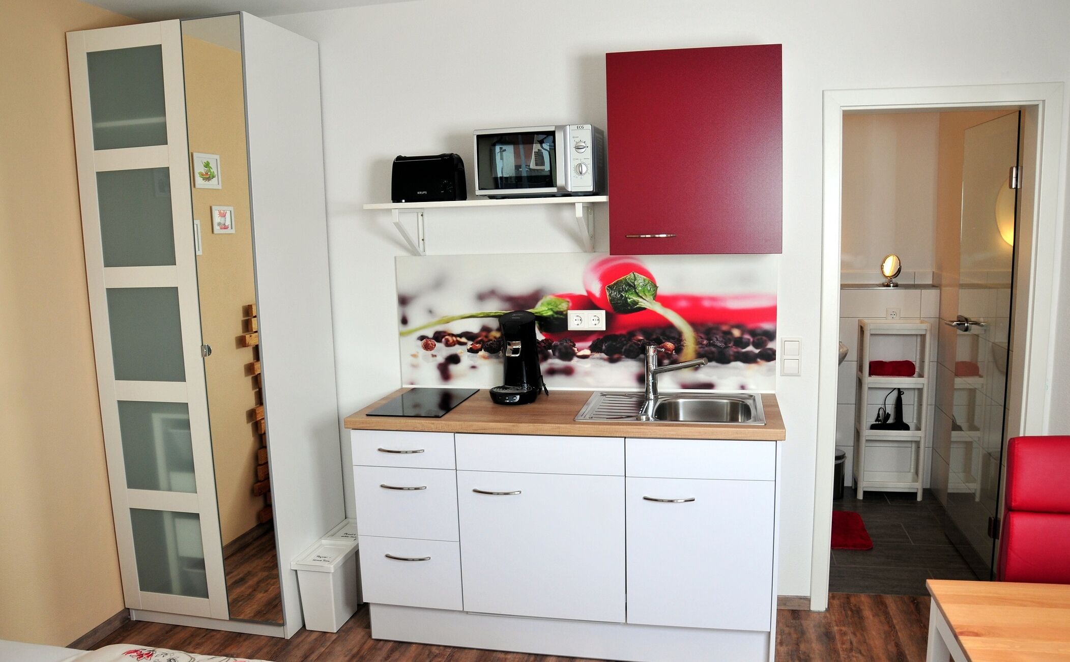 A compact kitchen with white cabinets, a microwave, a coffee maker, and a sink.