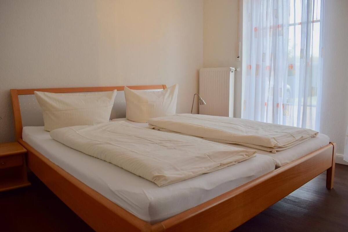 A double bed with a wooden frame, white bedding, and a nightstand.